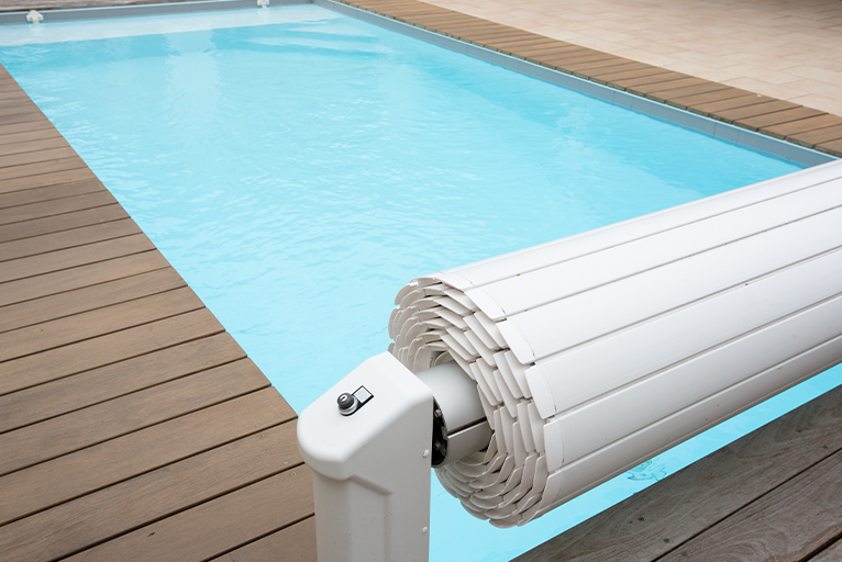 Pool cover fitted to one end of a rectangular swimming pool. 
