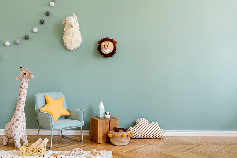 Nursery with muted green walls and soft animal toys
