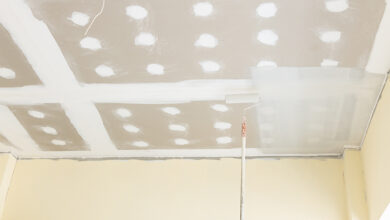 Mist coat being applied to plastered ceiling with roller brush.