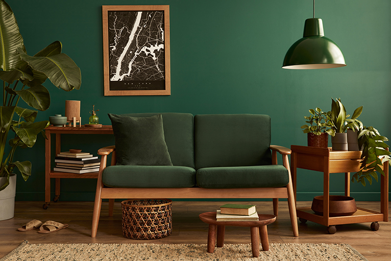 Lounge decorated in green and brown, with plants placed on either side of a sofa. 