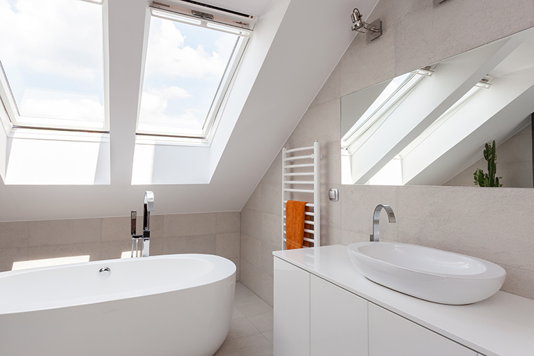 Skylight windows letting light into a white-painted, fresh modern bathroom. 
