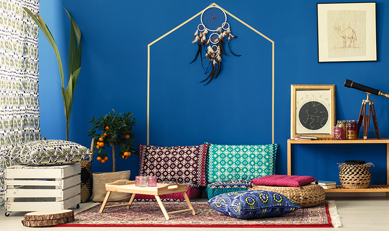 Boho inspired ground-level seating area with a rug, colourful cushions and a table tray. 