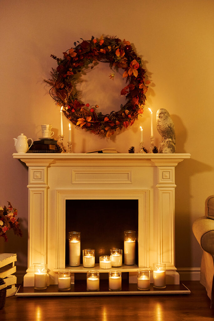 Large home fireplace, decorated with soft candles in glass jars.