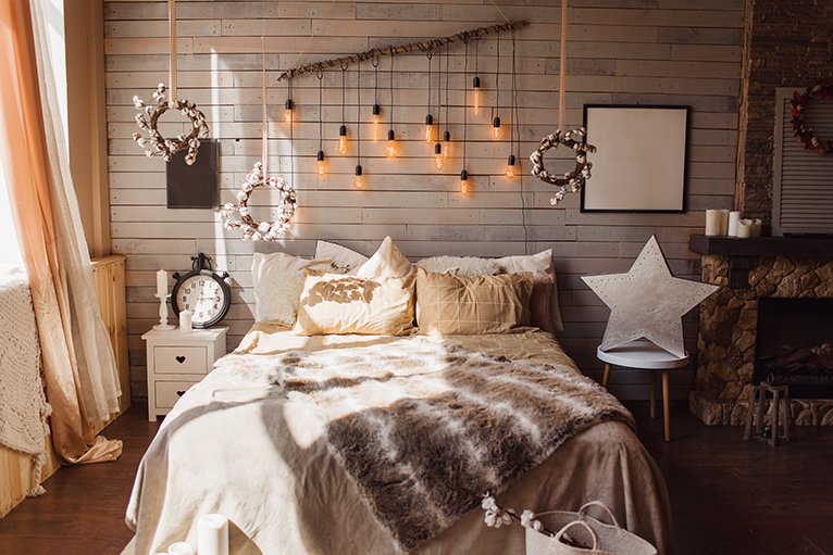 Cosy, autumnal inspired bedroom  interior with cosy throws and wooden hanging decor. 