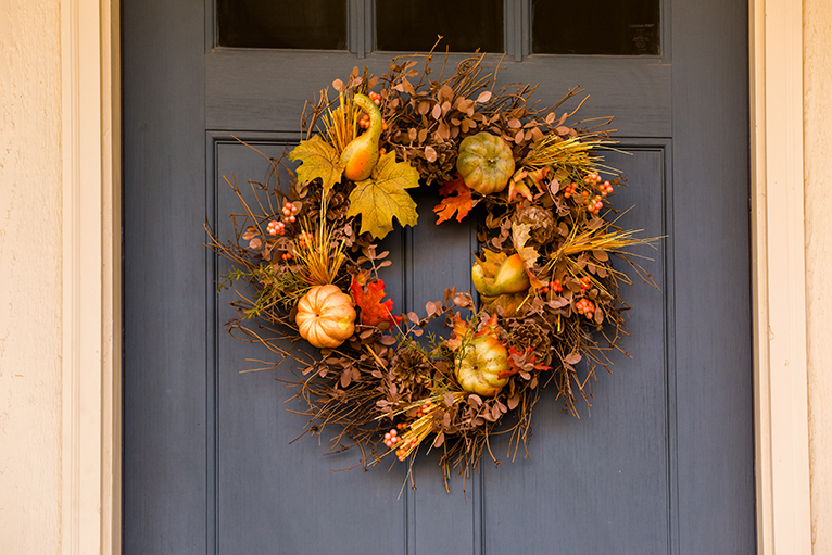 Autumnal floral wreath hung on the front door of a house.