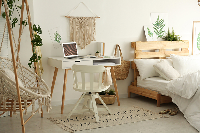 Boho style bedroom with wooden and rope egg chair and a white wooden office desk and chair set. 