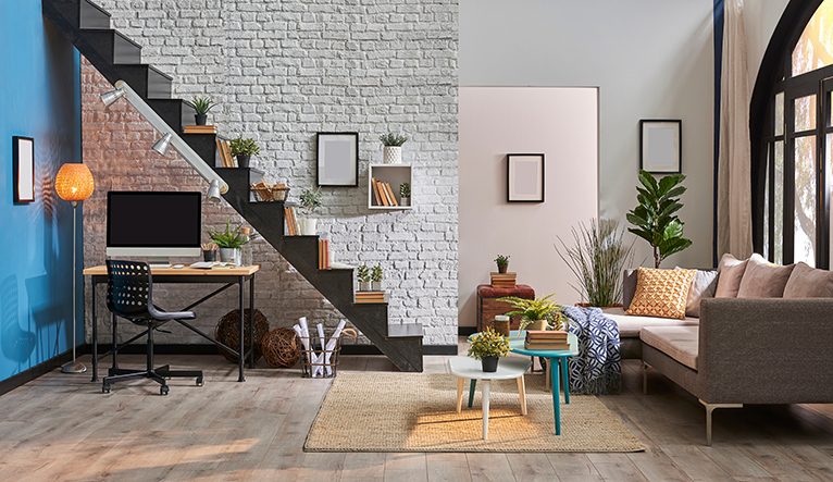 Modern living room with a white washed brick wall and wooden stair case with a small office space underneath. 