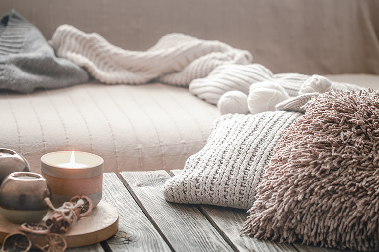Neutral-toned pillows and cosy winter throws draped on a couch. 
