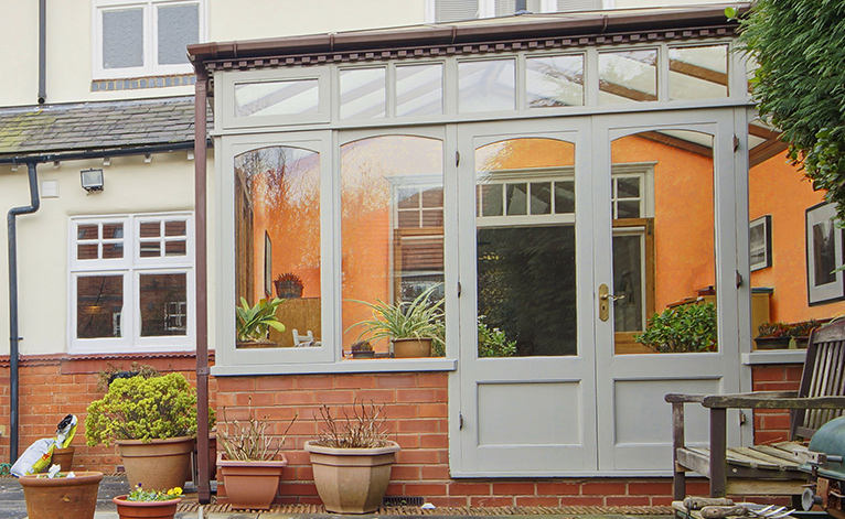 Conservatory with walls painted in a burnt orange shade. 