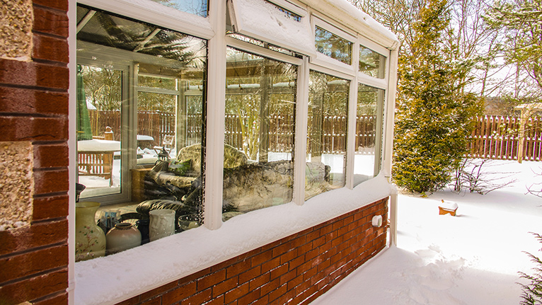 Outside view of a conservatory surrounded by thick winter snow.
