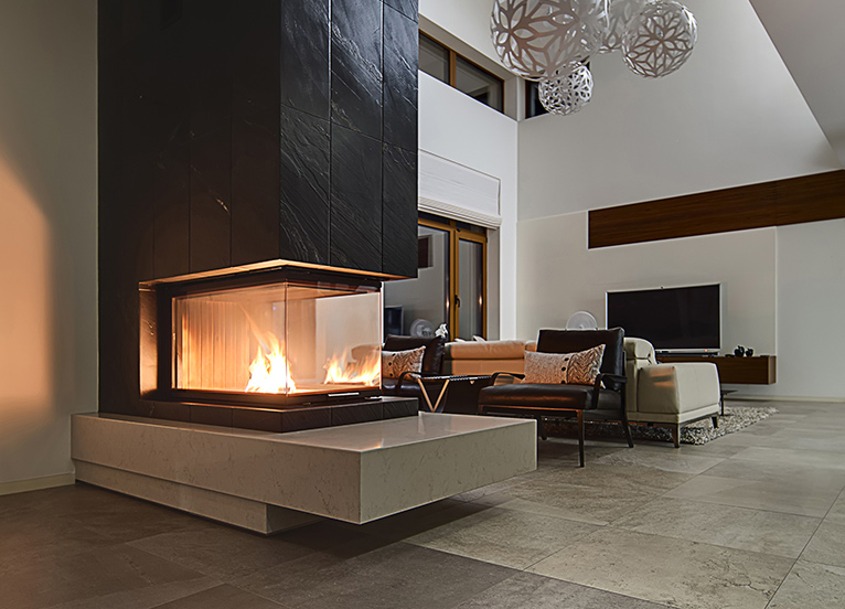 Large, modern electric glass box fireplace built into a partition wall of a living room. 