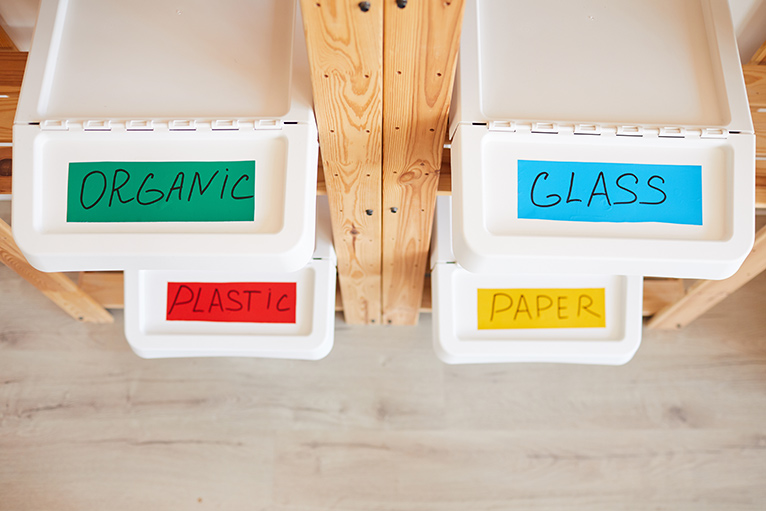 Recycling bins with different coloured labels for organics, glass, plastics and paper.