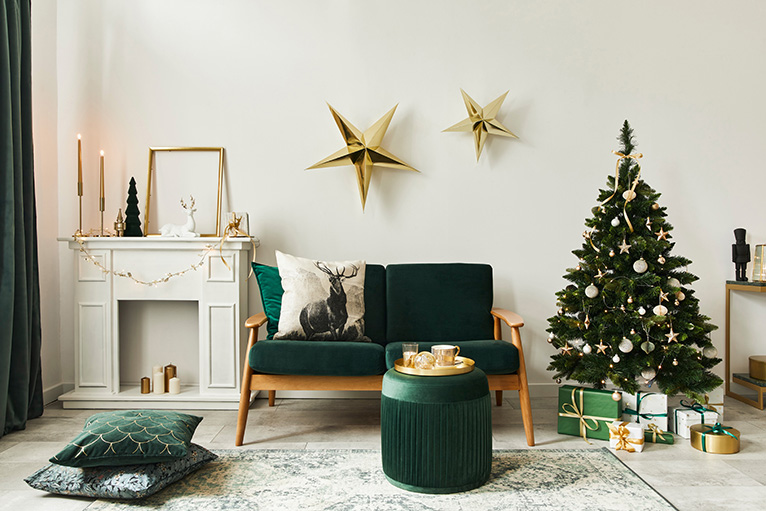 Emerald green winter decor. A green couch, pillows, foot stall and a Christmas tree with presents underneath.