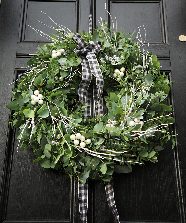 Large wreath made of eucalyptus, hanging on the front of a door.