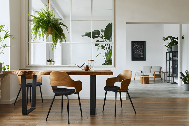 Clean and modern home interior with a wooden table and chairs and a hanging potted plant. 