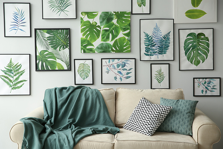 living room with hanging wall picturs of green leaves and a couch with a green coloured throw.