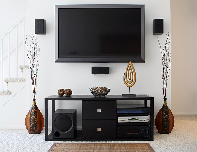 TV system set up with speakers and decorative ornaments disguising cables. 