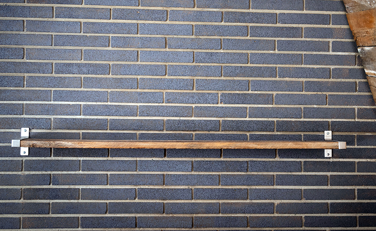 Wooden shelf hanging on a brick wall. 