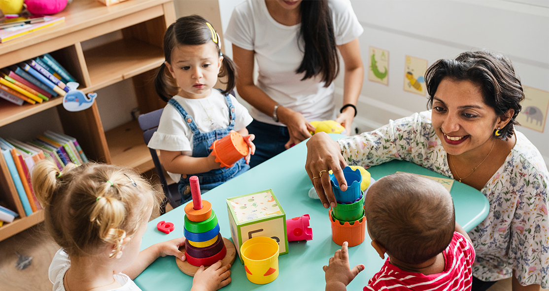 Nursery scene with three children and two childminders