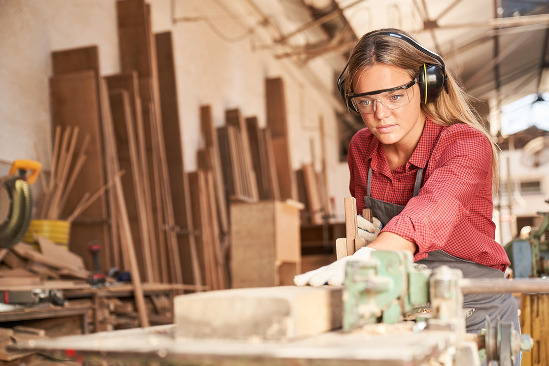 Woman carpenter working on a wooden board