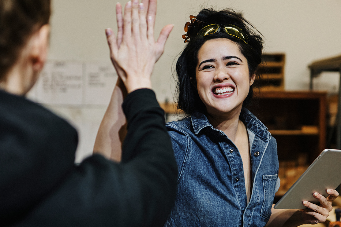 Smiling women carpenters high-fiving in workshop  