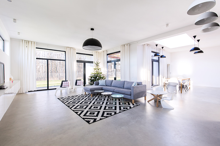 polished concrete floor in modern living room with neutral decor and l-shaped grey sofa
