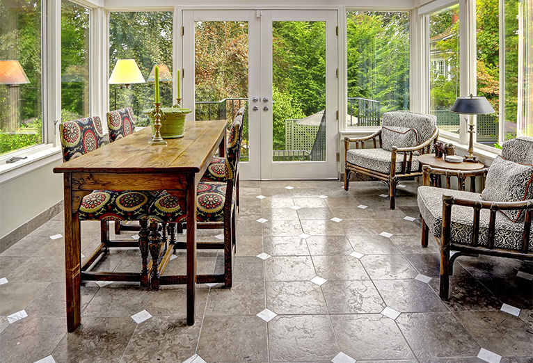 Inside an ornate orangery with decorative white and silver floor tiles and classic wooden furniture