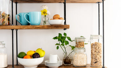 Wooden shelves with glass jars and fruit in a bowl