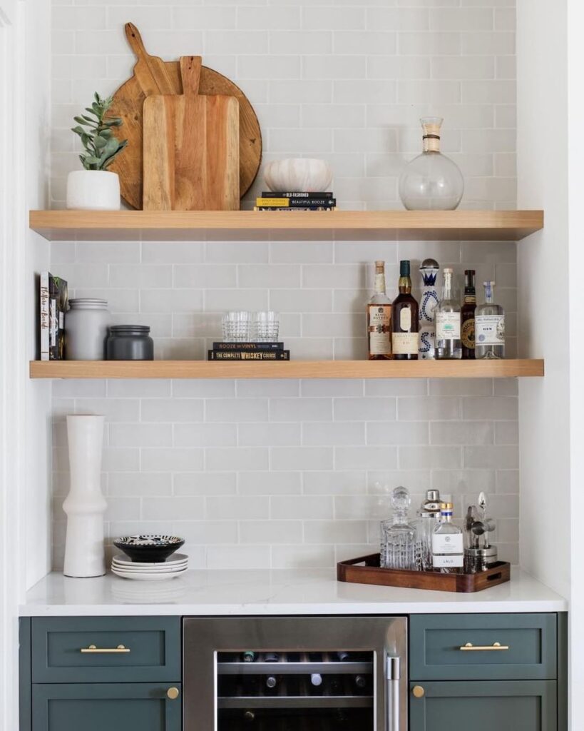 a wet bar with tiled backsplash and wooden free standing shelves with alcohol bottles on them