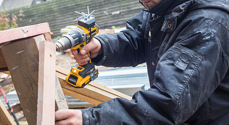 photo of a builder drilling two bits of wood together to form a frame for a house extension