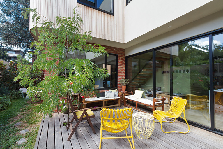 Wooden decking with garden furniture by a brick and wood panelling extension