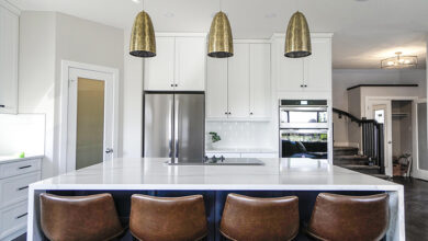 White kitchen with stool at a bar section and gold hanging lamps