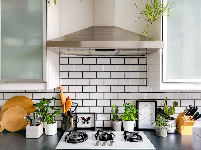 Black and white subway tiled kitchen with numerous plants on counter tops. The subway tile grouting has been painted black.