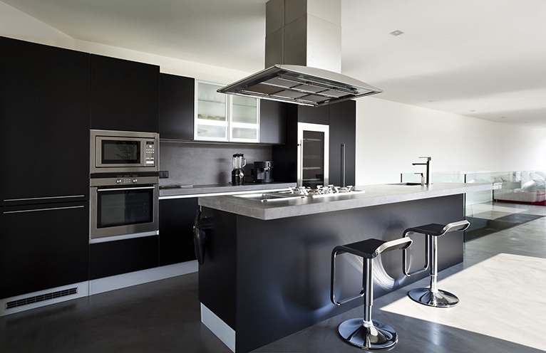 Modern, dark kitchen with light stone worktop.
