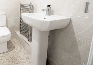 Photo of a bathroom with a full pedestal basin, mixer tap, toilet and towel warmer.