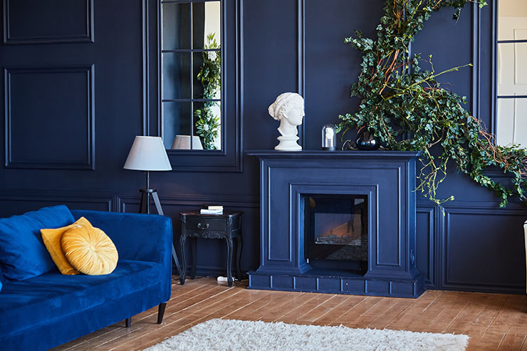 Modern interior with fireplace, spacious living room with dark blue walls and wooden floor. A real photo of the interior.