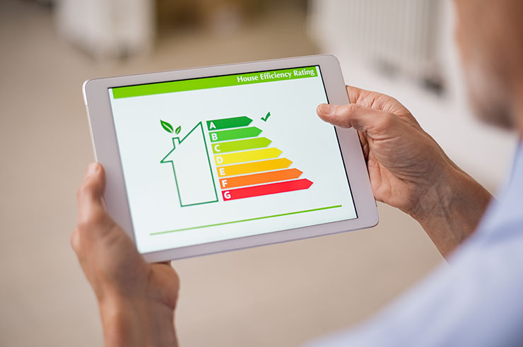 Man holding a digital tablet with an image representing house efficiency rating.