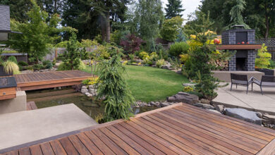 Backyard garden with a wooden deck, trees, and flowers.
