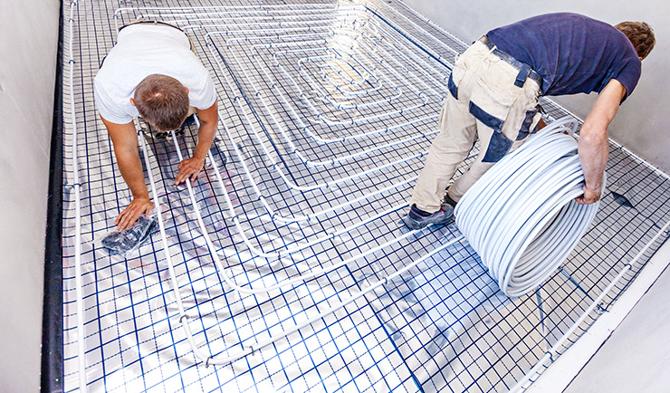 Picture of two men installing underfloor heating in a kitchen