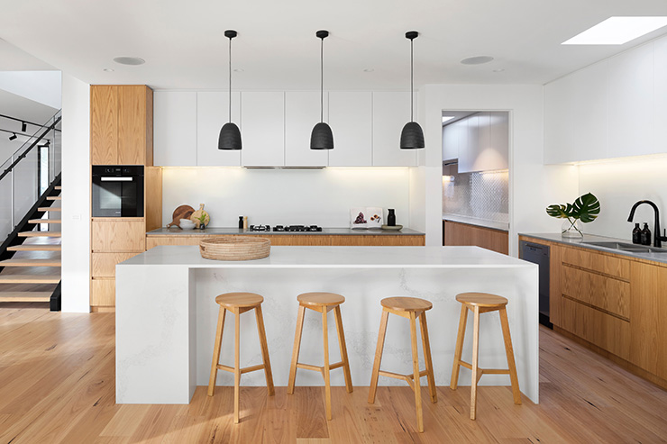 Picture of a kitchen with a worktop counter, stools, overhead lights and wooden floors