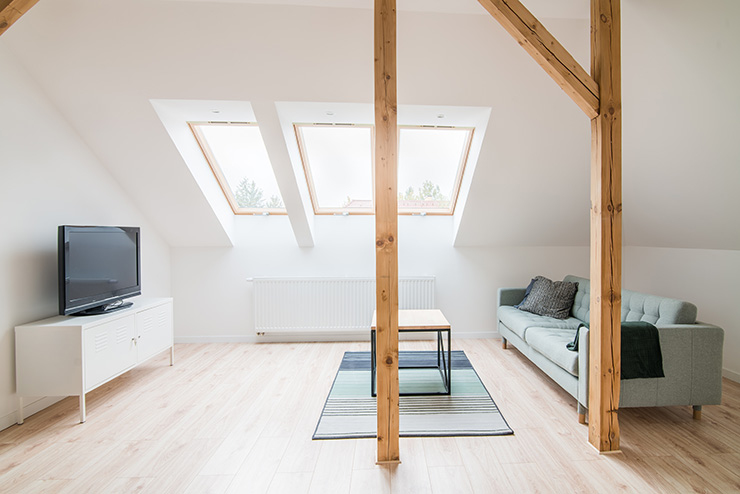 Picture of a loft conversion being used as a lounge area with a sofa, TV, and skylight