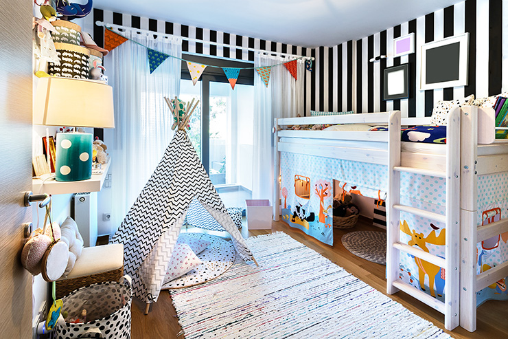 Kids bedroom with wooden bunk bed painted white, a teepee tent is on the floor like a den, and there is a cotton rug on the floor.