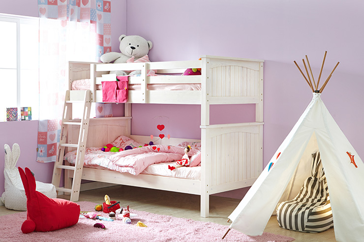 Interior of child's bedroom with bunk bed against the wall. The room is painted pink and decorated with stuffed toys. There is also a pink fluffy rug on the floor with some toys out and a teepee den to the right of the bed.