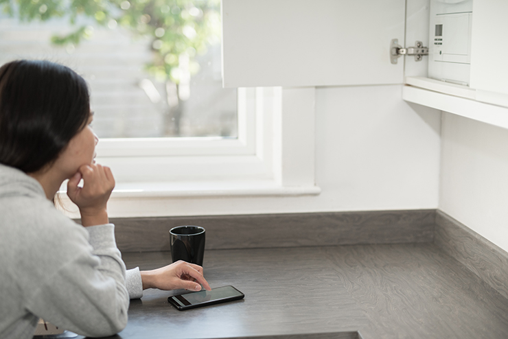 Picture of a woman adjusting the temperature of her boiler using her mobile phone