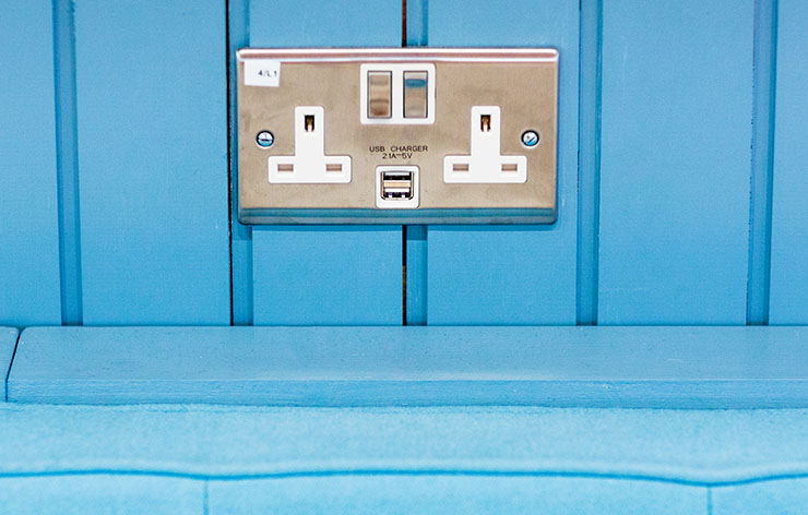 Picture of a plug socket on a blue wall