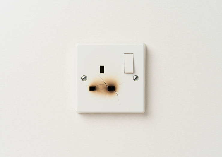 Picture of a damaged electrical domestic power socket with cracks and burn marks