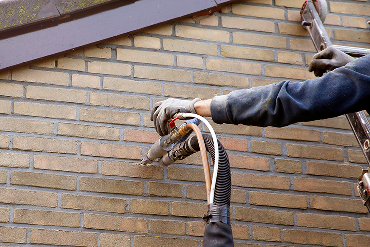 Picture of a tradesperson installing cavity wall insulation in a outer wall