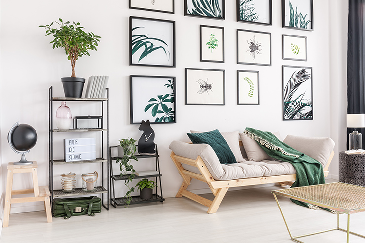 Picture of a living room with green plant themed paintings on the wall and a sofa