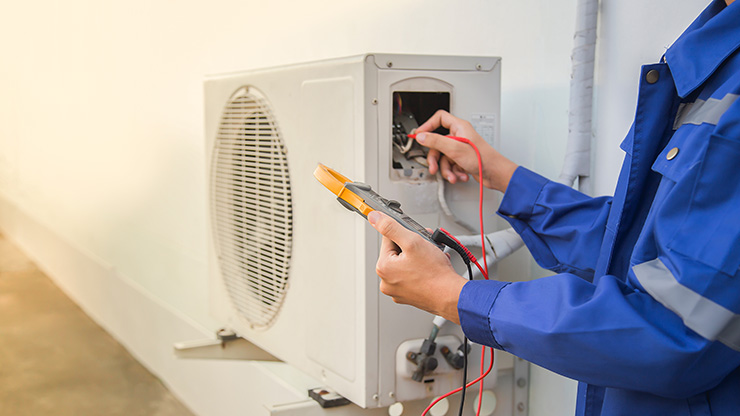 Picture of a tradesperson servicing an air conditioning unit