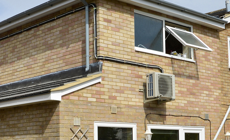 Picture of the outside of a home with an air con unit attached to one of the walls